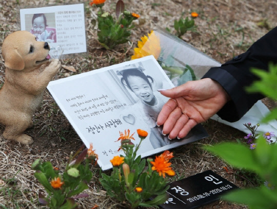 경기도 양평군 하이패밀리 안데르센 공원묘원에서 한 시민이 양부모의 학대로 생후 16개월 만에 사망한 정인이의 사진을 어루만지고 있다.   연합뉴스